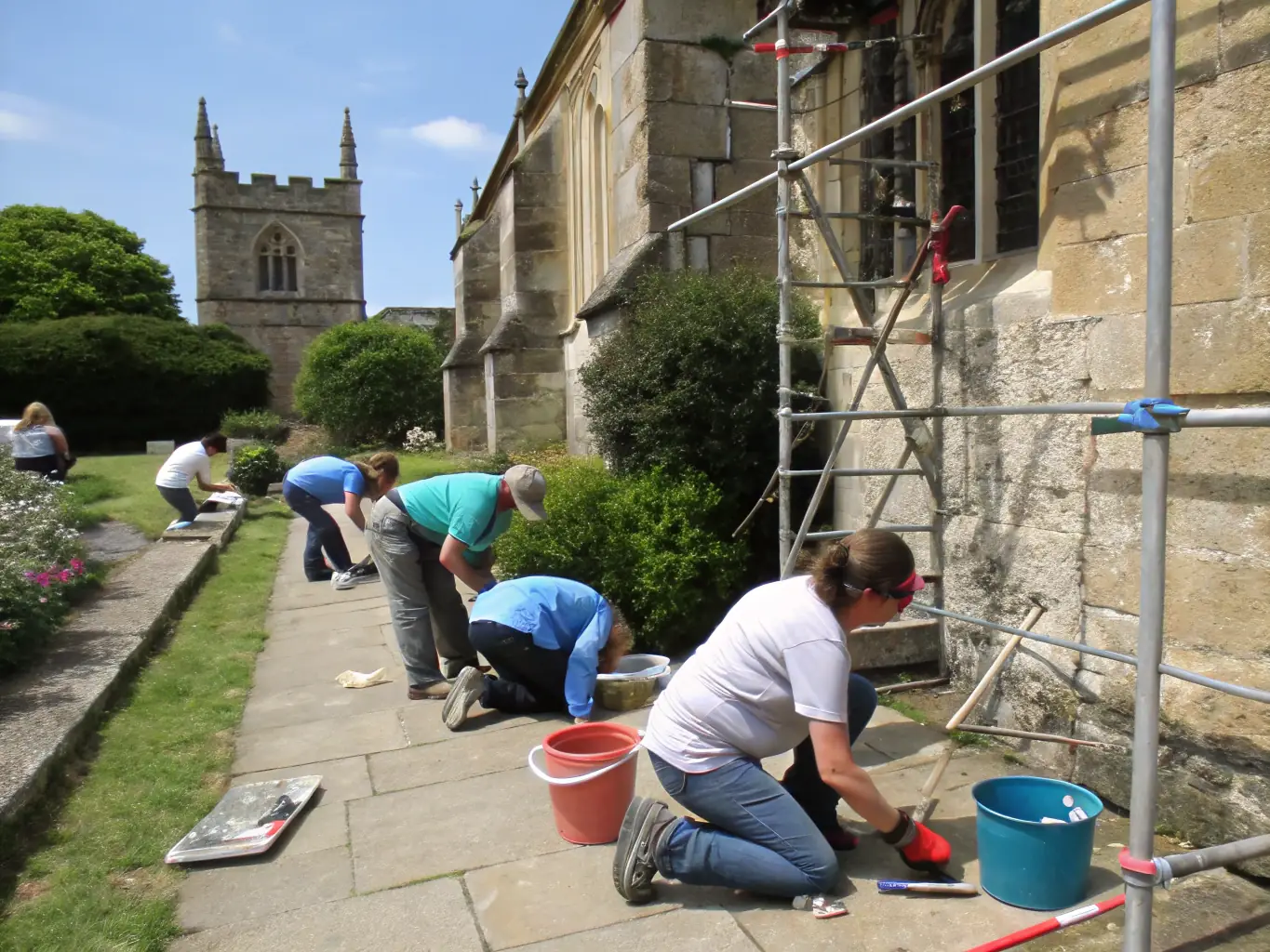 A photo of volunteers working on restoration scaffolding around the Château de Lioujas, highlighting active preservation efforts.